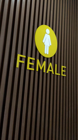 Clear female restroom sign mounted on a modern wooden panel wall. Minimalist public facility signage suitable for themes of architecture, interior design, and wayfinding.の写真素材