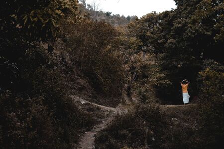 Man walking in forest carrying woods on his headの写真素材