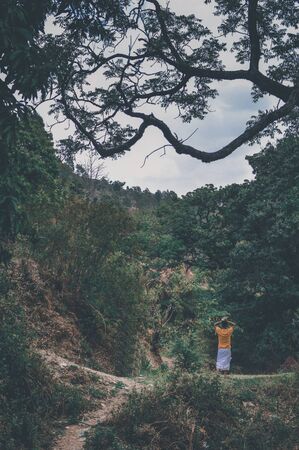 Man walking in forest carrying woods on his headの写真素材