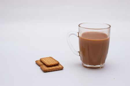 Three biscuits placed on a white background along with a cup of teaの写真素材