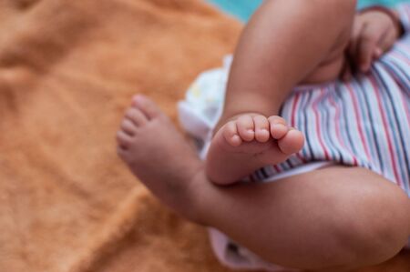 Small feet of a small baby folded over each other on a orange backgroundの写真素材