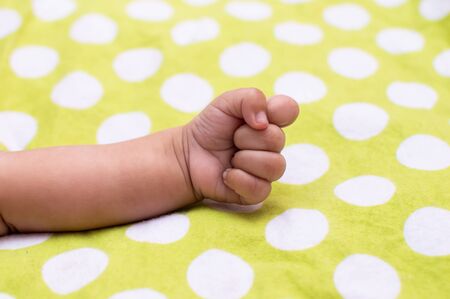 A closed fist and forearm of an infant on a polka dotted backgroundの写真素材