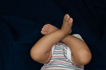 Small legs of an infant lying on a blue clothの写真素材