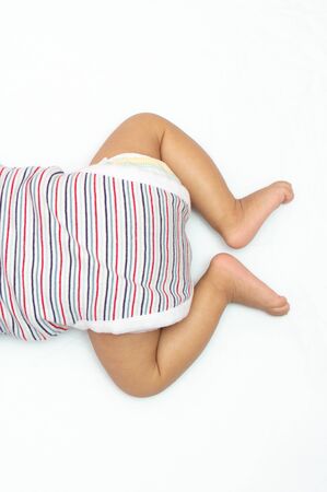 Infant lying on his chest on white background with open legs over head photoの写真素材