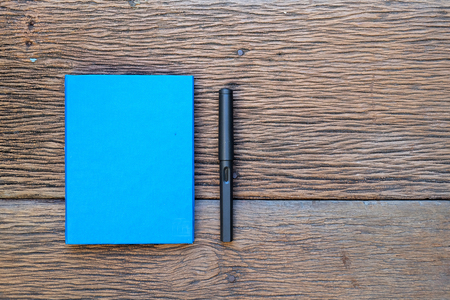 A blue notebook and fountain pen on woodの写真素材