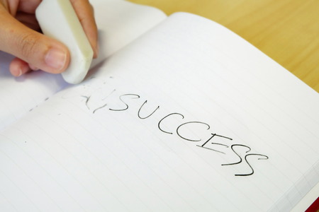 Hand holding eraser and erase letters "UN" from wordの写真素材