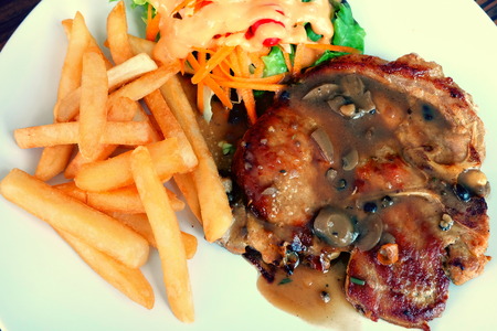 Pork chop steak with french fries and saladの写真素材