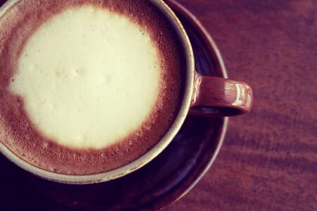 A cup of coffee cappuccino on a wooden tableの写真素材
