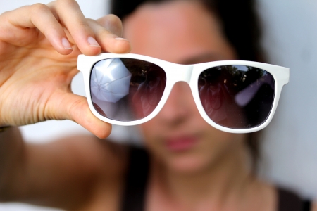 young woman holding sunglassesの写真素材
