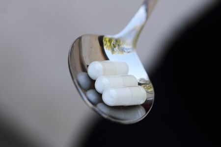 a spoon with plain white capsulesの写真素材