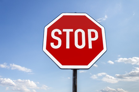 stop sign in front of a cloudy summer sky