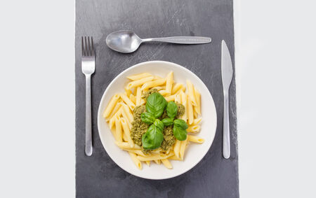 pasta with pesto in a plate on a tableの写真素材