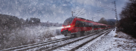 red train speeding in the snowの写真素材