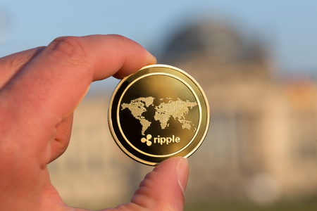 ripple coin in a hand in front of german bundestag berlinの写真素材