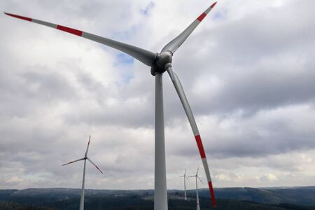 wind wheels in front a forest hills landscapeの写真素材