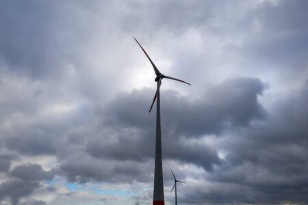 two wind wheels in front a dark cloudscapeの写真素材