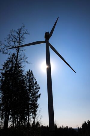 modern wind turbine in front of the evening sun uprightの写真素材