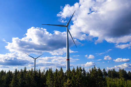 modern wind turbines in front of a blue and cloudy skyの写真素材