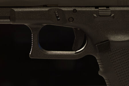 A closeup view of a semi-automatic pistol trigger. On black background.の写真素材