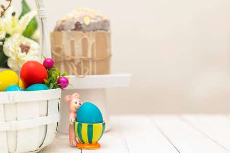 Easter background with basket full of colorful eggs, easter bunny and easter cake (aka: Orthodox sweet bread, kulich or Paska). Copy space for text. Wooden background.の写真素材