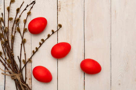 Red easter eggs on white wooden table with branch of willow. Easter backgrounds with copy space for text. Top view. Greeting card. Happy easter concept.の写真素材