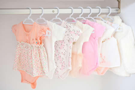 Colorful, cute girl baby dresses hanging on rack in wardrobe. Baby fashion concept design.の写真素材