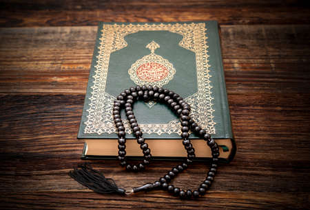 Holy Islamic Book Koran with rosary beads on wooden background. Quran with written arabic calligraphy meaning of Al Quran. Ramadan Mubarak. Ramadan kareem.の写真素材