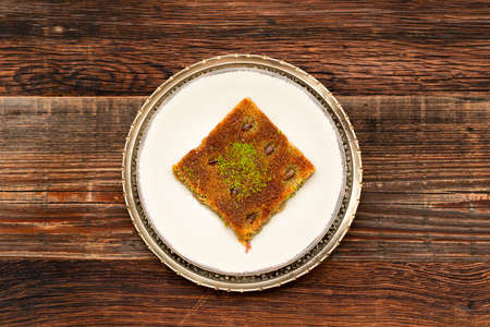 Closeup of traditional Turkish dessert - Kadayif with pistachio powder (Burma kadayif) on wooden...