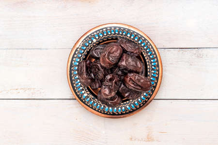 Fresh date fruits in ottoman handmade bowl on wooden background. Healthy food. Fast food. Food for...