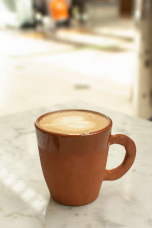 Cup of hot aroma coffee latte in coffee shop on the table. Blurred background with copy space.