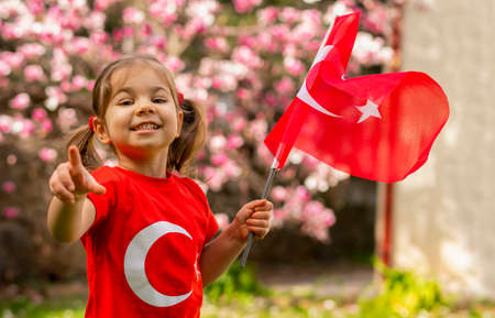 Cute little girl in a red T-shirt with a Turkish flag on the background of a blooming tree.の写真素材