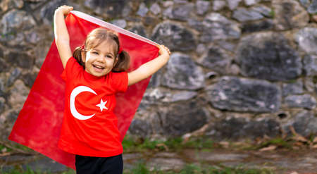 Little girl with a Turkish flag on the background of a stone wallの写真素材
