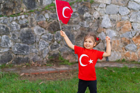 Little girl with a Turkish flag in her hands, on the background of an old stone wallの写真素材