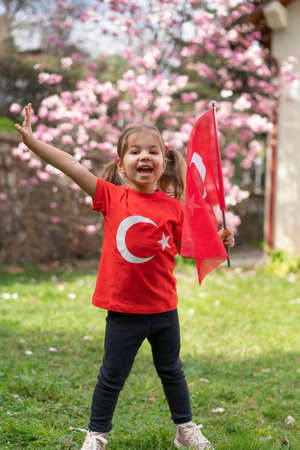 A little girl with a Turkish flag in her hands stands in the park.の写真素材