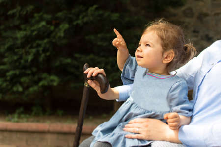 Little girl sitting with her mother and pointing at somethingの写真素材