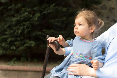 Little girl sitting on a walking stick with her mother in the park