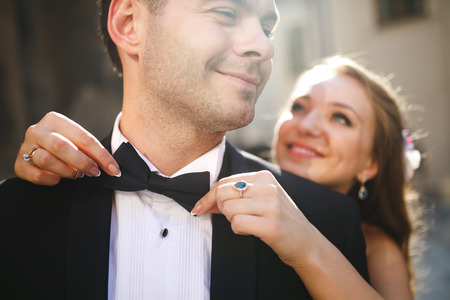 Bride standing behind groom gently embracing and smilingの写真素材