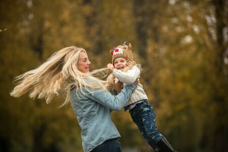 mother and daughter having fun in autumn parkの写真素材