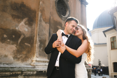 Bride standing behind groom gently embracing and smilingの写真素材