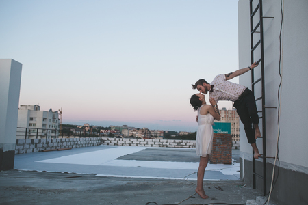 beautiful couple together on the roof of a tall buildingの写真素材