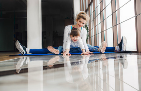 Mother and daughter hugs and stretch in the gymの写真素材