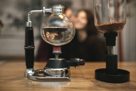 Vintage couple preparing coffee with vacuum coffee maker.Coffee shop.  Vintage tonedの写真素材