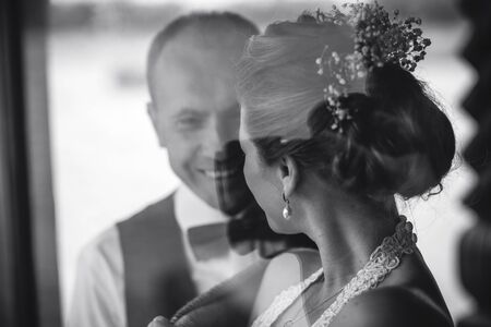 Wedding couple together close to each other at the windowの写真素材