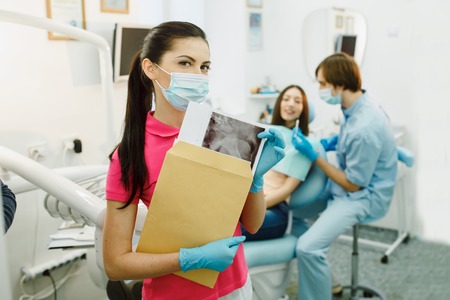 dentist and assistant in his office taking patientの写真素材