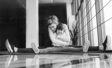 Mother and daughter hugs and stretch in the gymの写真素材