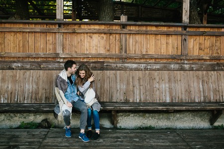 Young couple in love wrapped in plaid sitting and having funの写真素材