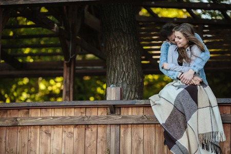 Young couple in love wrapped in plaid standing and embraceの写真素材