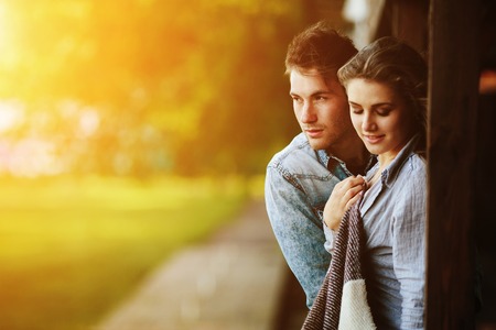 Young couple in love wrapped in plaid standing and embraceの写真素材