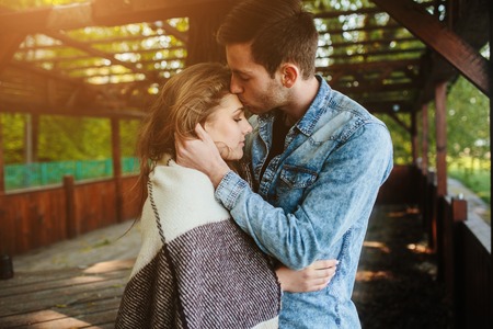 Young couple in love wrapped in plaid standing and kissingの写真素材