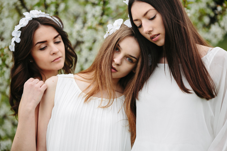 three beautiful girls posing in the garden at the cameraの写真素材